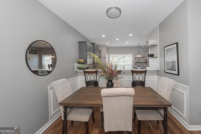 dining space with recessed lighting, a wainscoted wall, dark wood-type flooring, and a decorative wall