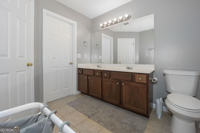 bathroom featuring tile patterned floors, a sink, toilet, and double vanity