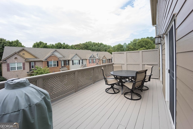 wooden terrace with grilling area, outdoor dining space, and a residential view