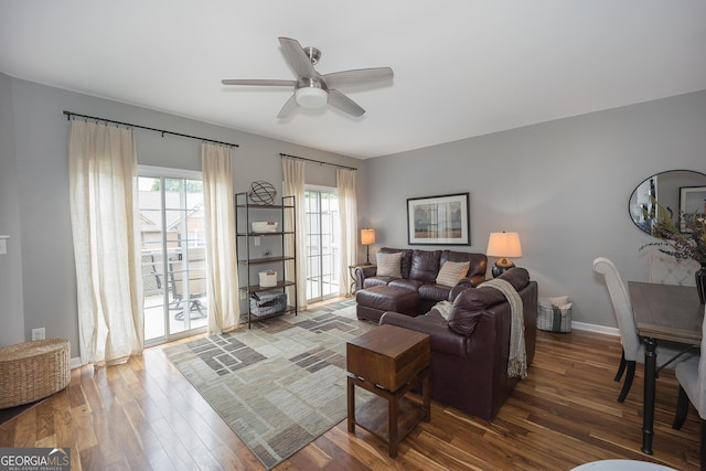 living area with baseboards, a ceiling fan, and wood finished floors