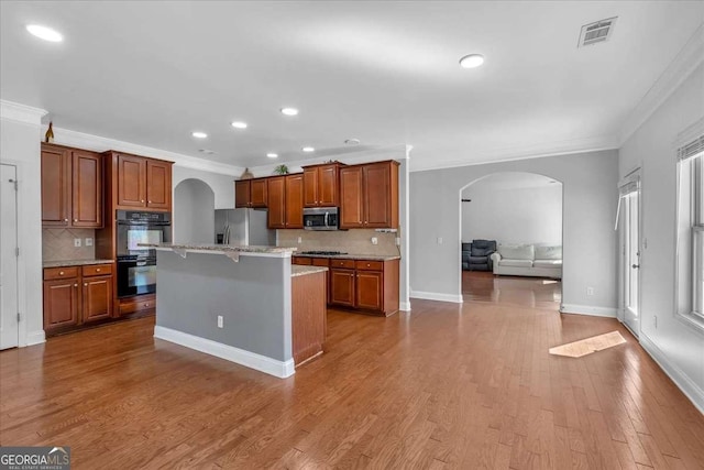 kitchen with wood finished floors, visible vents, arched walkways, appliances with stainless steel finishes, and open floor plan