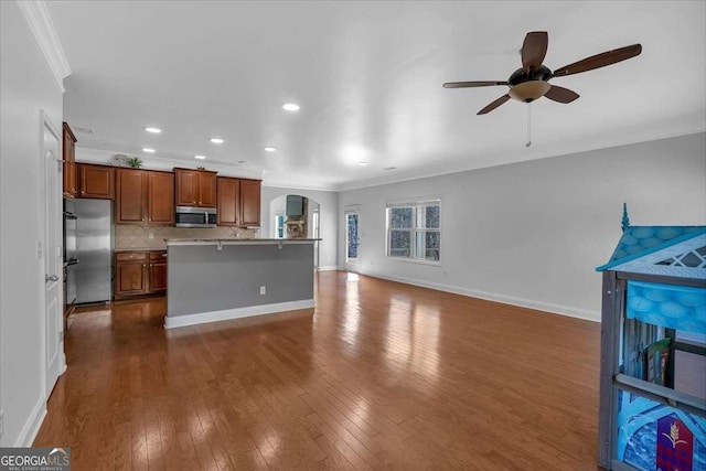 kitchen with open floor plan, decorative backsplash, dark wood-style floors, appliances with stainless steel finishes, and arched walkways