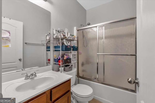 bathroom with vanity, toilet, and combined bath / shower with glass door