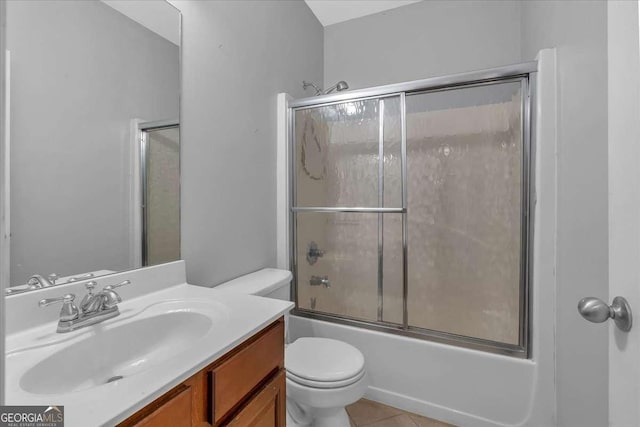 bathroom with bath / shower combo with glass door, toilet, vanity, and tile patterned flooring