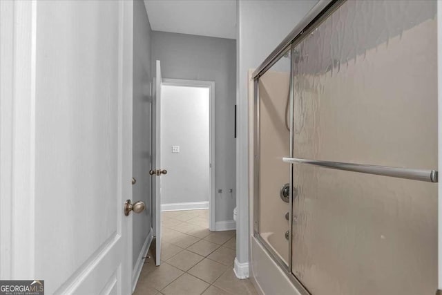 bathroom featuring tile patterned floors, combined bath / shower with glass door, toilet, and baseboards