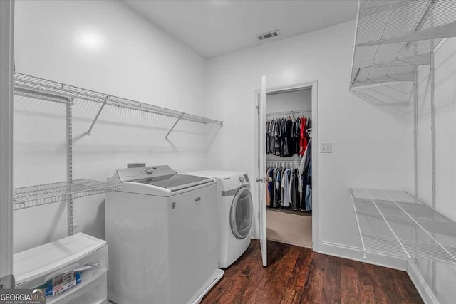 clothes washing area with baseboards, visible vents, washing machine and clothes dryer, laundry area, and dark wood-type flooring