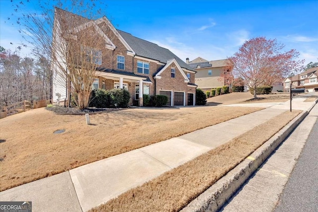 view of front facade featuring brick siding, fence, a residential view, a front yard, and an attached garage