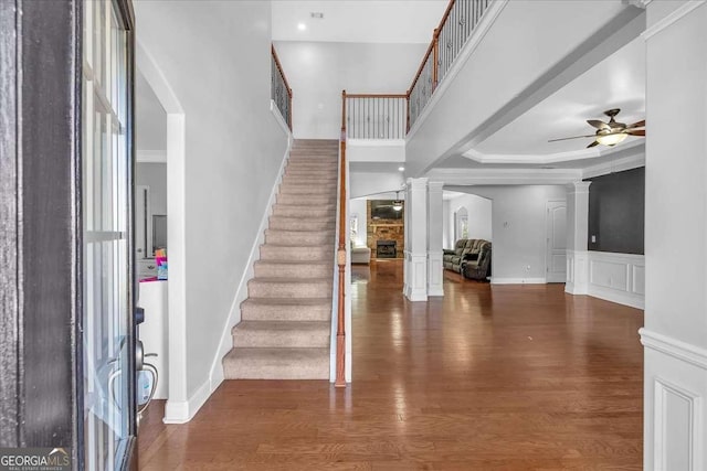 foyer entrance with stairway, decorative columns, wood finished floors, a decorative wall, and a ceiling fan