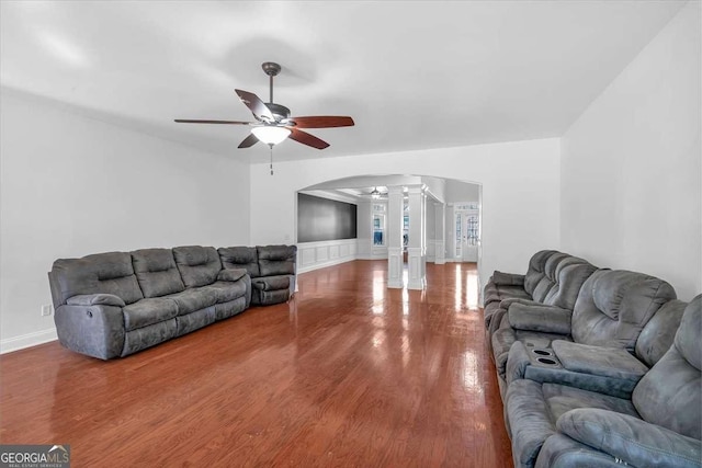 living room with arched walkways, wood finished floors, a ceiling fan, and decorative columns