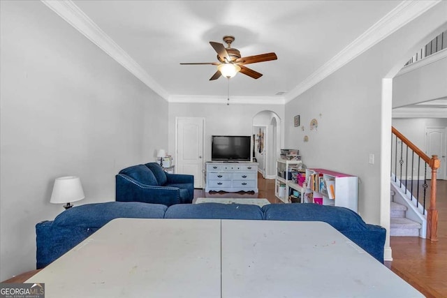 living room with stairway, ornamental molding, arched walkways, and ceiling fan