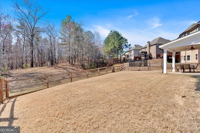 view of yard featuring a patio, a ceiling fan, a trampoline, and fence