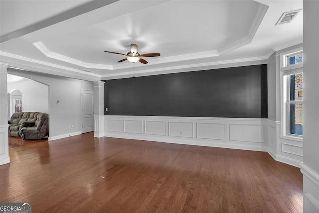 spare room with visible vents, a raised ceiling, ceiling fan, and dark wood finished floors