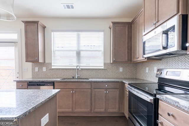 kitchen with visible vents, dark wood finished floors, decorative backsplash, stainless steel appliances, and a sink