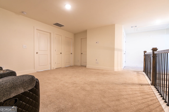 living area with attic access, baseboards, visible vents, and light carpet