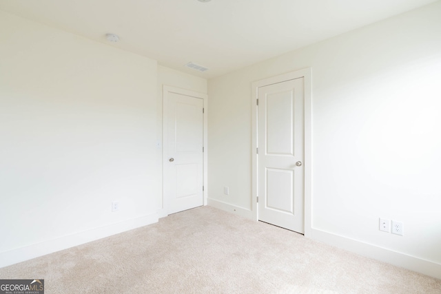 carpeted spare room with visible vents and baseboards