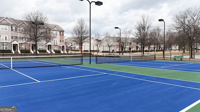 view of tennis court with a residential view, community basketball court, and fence