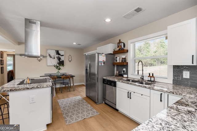 kitchen featuring visible vents, island exhaust hood, a sink, appliances with stainless steel finishes, and white cabinetry