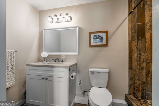 bathroom featuring a tile shower, toilet, and vanity