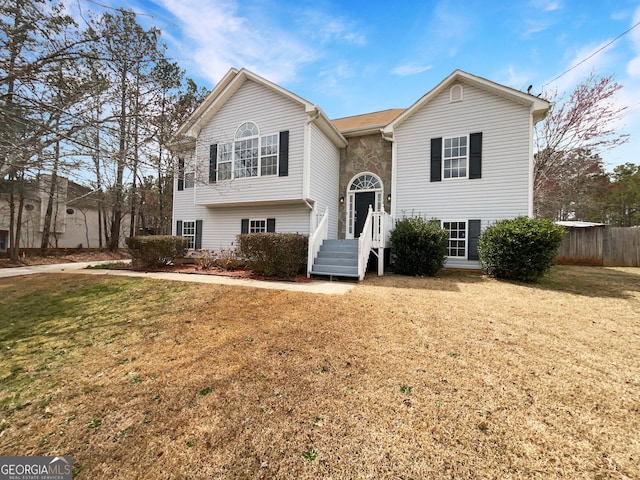 raised ranch with a front lawn and fence