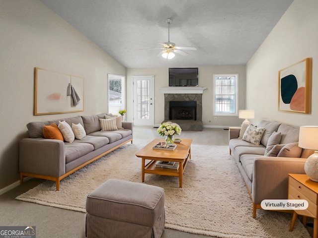 living room featuring a fireplace with raised hearth, ceiling fan, baseboards, carpet, and vaulted ceiling