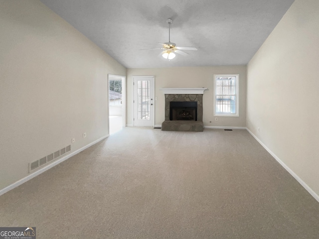 unfurnished living room featuring visible vents, carpet floors, a fireplace, ceiling fan, and vaulted ceiling