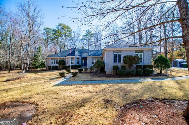 view of front of house with an outbuilding, brick siding, and a front yard