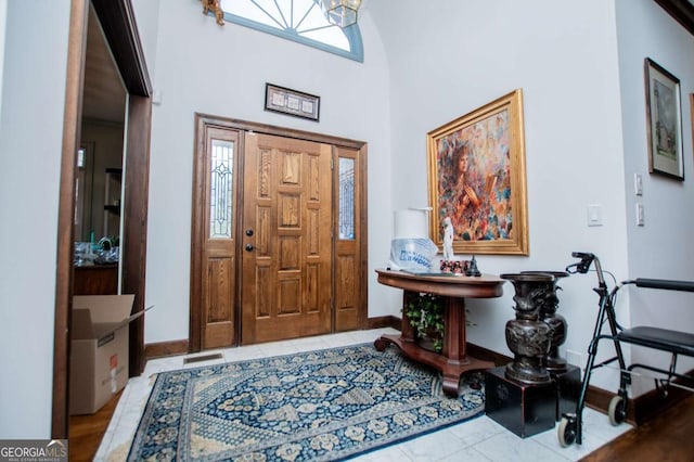 foyer featuring tile patterned flooring, baseboards, and a towering ceiling