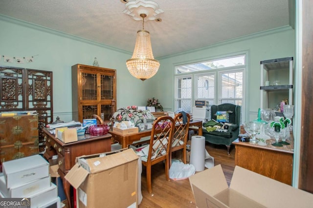 dining room with a textured ceiling, an inviting chandelier, wood finished floors, and ornamental molding