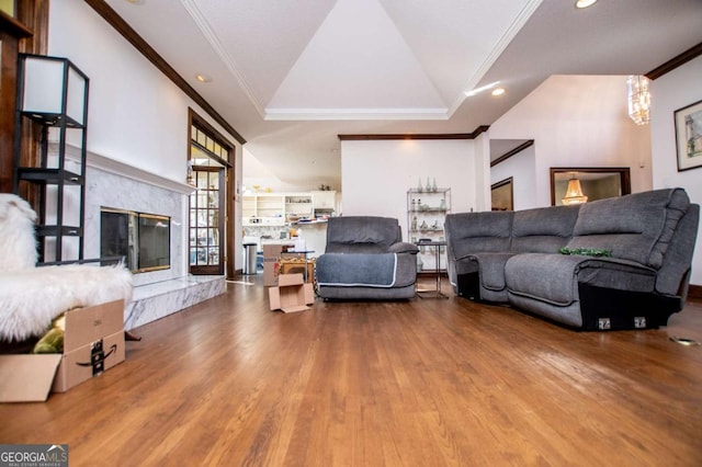 living room featuring wood finished floors, recessed lighting, crown molding, a premium fireplace, and vaulted ceiling