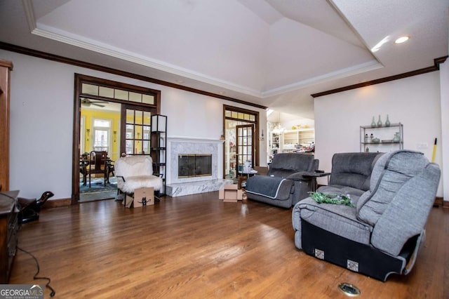 living area with a fireplace, french doors, a tray ceiling, and wood finished floors