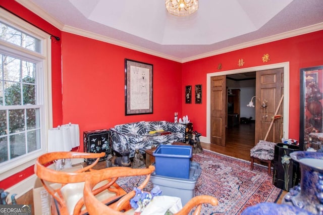 living area with crown molding, wood finished floors, baseboards, and a tray ceiling