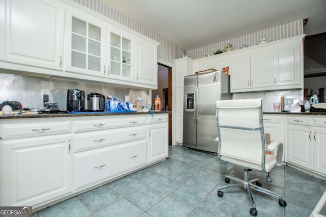 kitchen featuring wallpapered walls, glass insert cabinets, stainless steel refrigerator with ice dispenser, light tile patterned flooring, and white cabinets