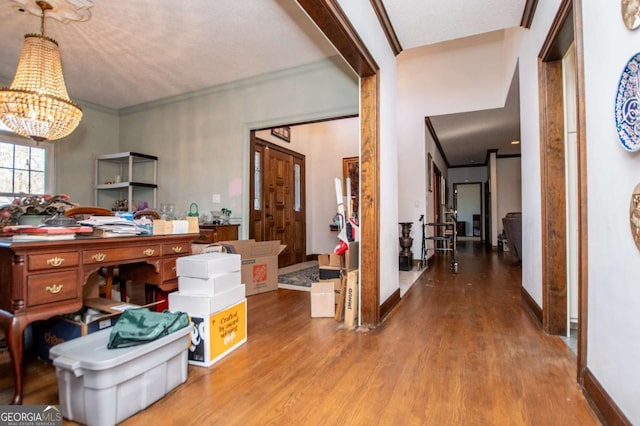 home office featuring crown molding, a notable chandelier, wood finished floors, and baseboards