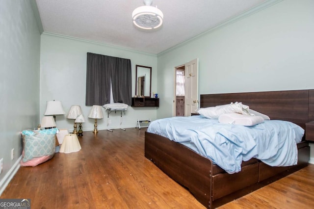 bedroom featuring crown molding, wood finished floors, baseboards, and a textured ceiling