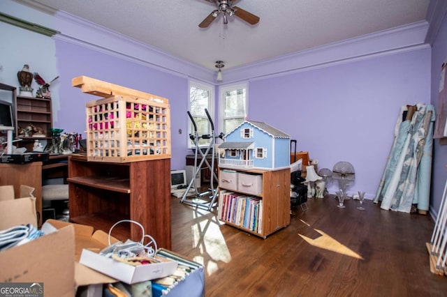 home office with wood finished floors, ornamental molding, and a ceiling fan