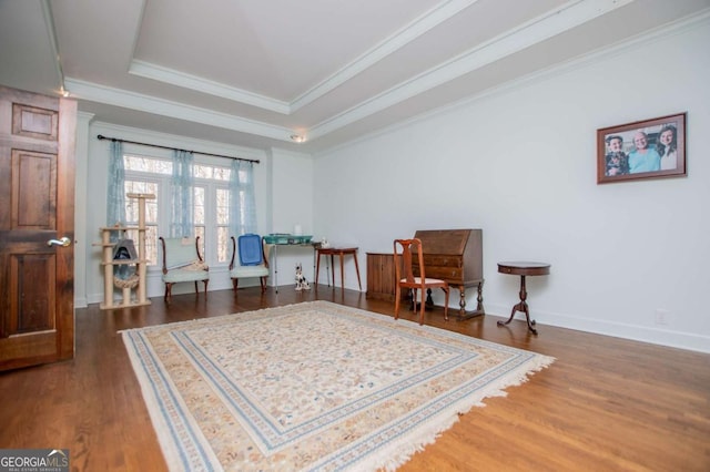 living area featuring ornamental molding, baseboards, a tray ceiling, and wood finished floors