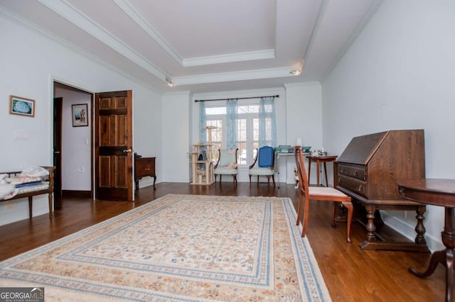 sitting room with ornamental molding, a raised ceiling, baseboards, and wood finished floors