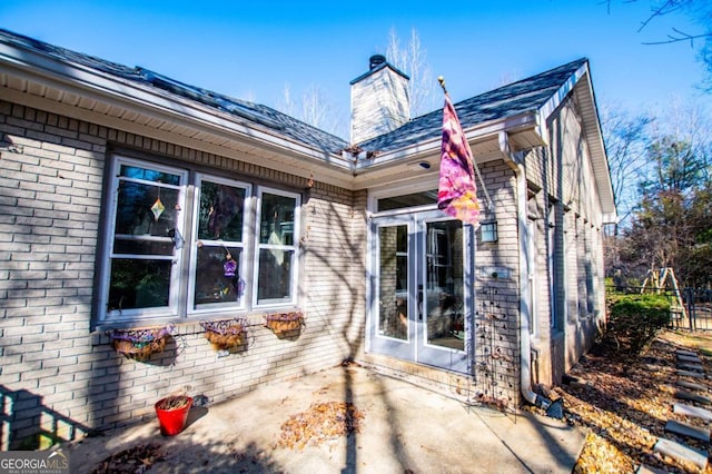 rear view of property featuring a patio area, brick siding, and a chimney