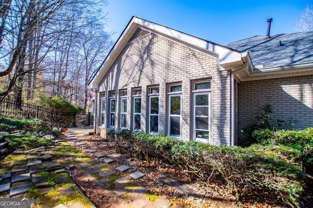 view of side of home with brick siding and fence