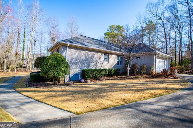 view of home's exterior featuring a garage, brick siding, concrete driveway, and a lawn