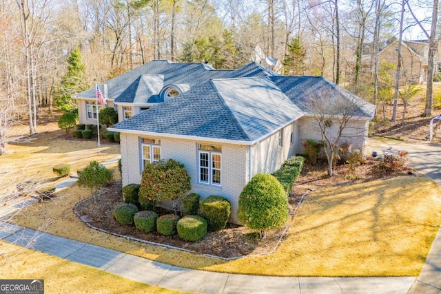 view of side of home featuring brick siding and roof with shingles