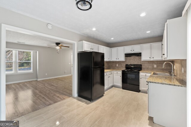 kitchen with under cabinet range hood, black appliances, tasteful backsplash, and a sink