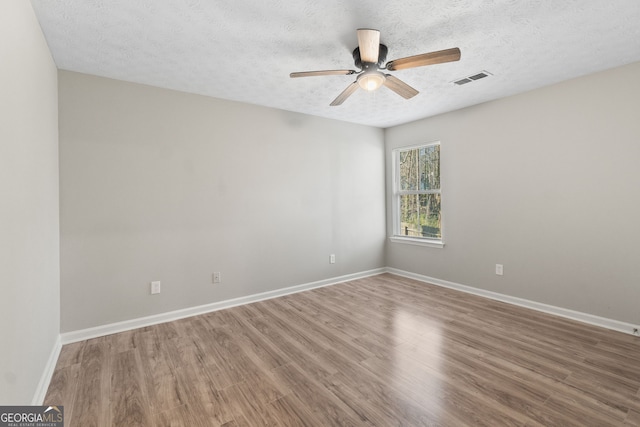 spare room featuring a textured ceiling, baseboards, a ceiling fan, and wood finished floors