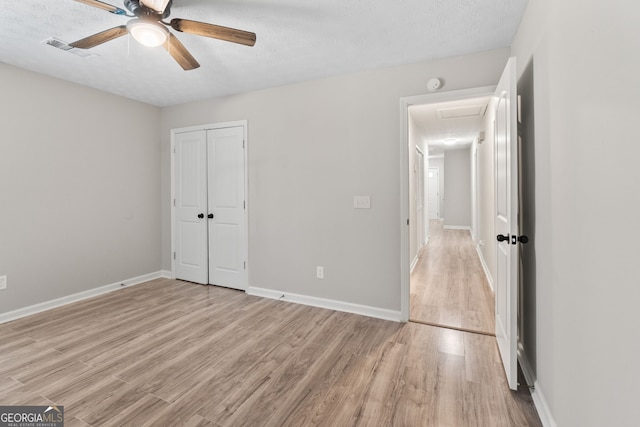 unfurnished bedroom featuring visible vents, baseboards, light wood-style floors, and a closet