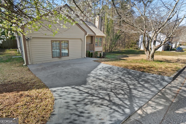 view of front of home featuring a front yard, a chimney, and driveway