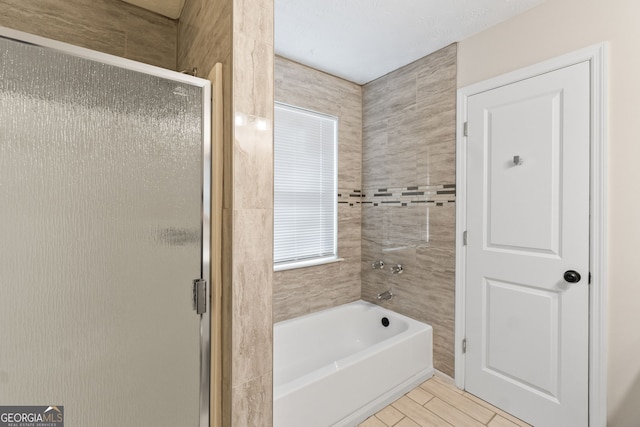 full bathroom featuring a bath, a stall shower, and wood finish floors