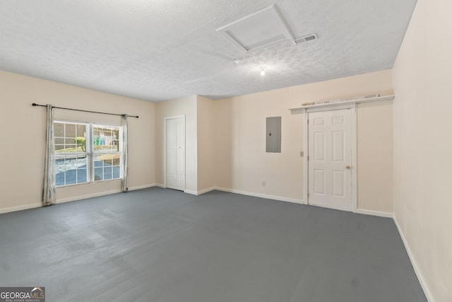 unfurnished room featuring visible vents, electric panel, a textured ceiling, baseboards, and attic access