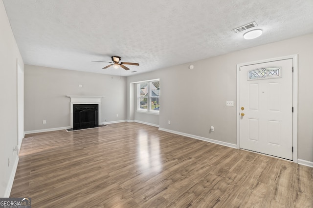 unfurnished living room with visible vents, wood finished floors, a textured ceiling, and ceiling fan