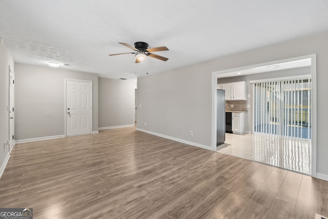 unfurnished living room featuring light wood-style flooring, baseboards, and ceiling fan