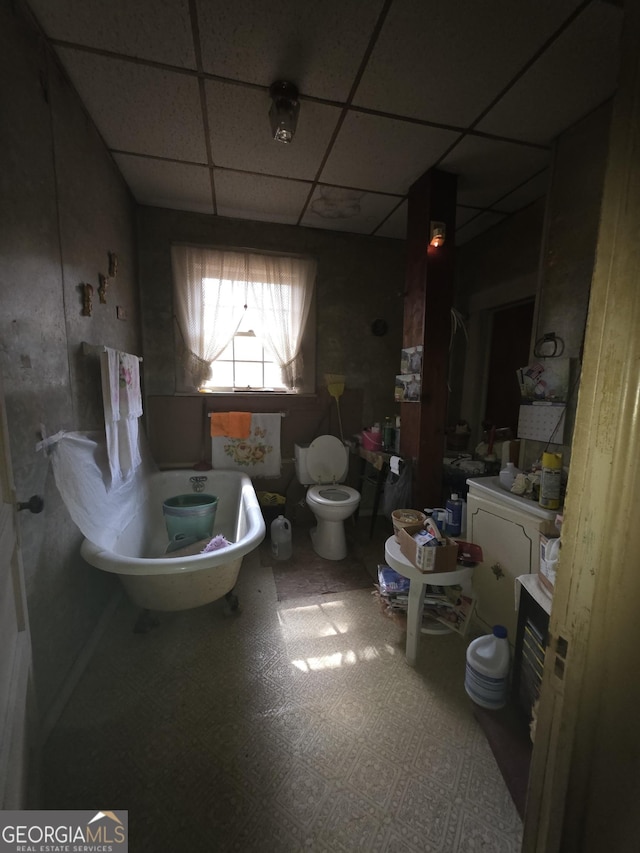 full bath with tile patterned floors, a freestanding tub, toilet, a paneled ceiling, and vanity